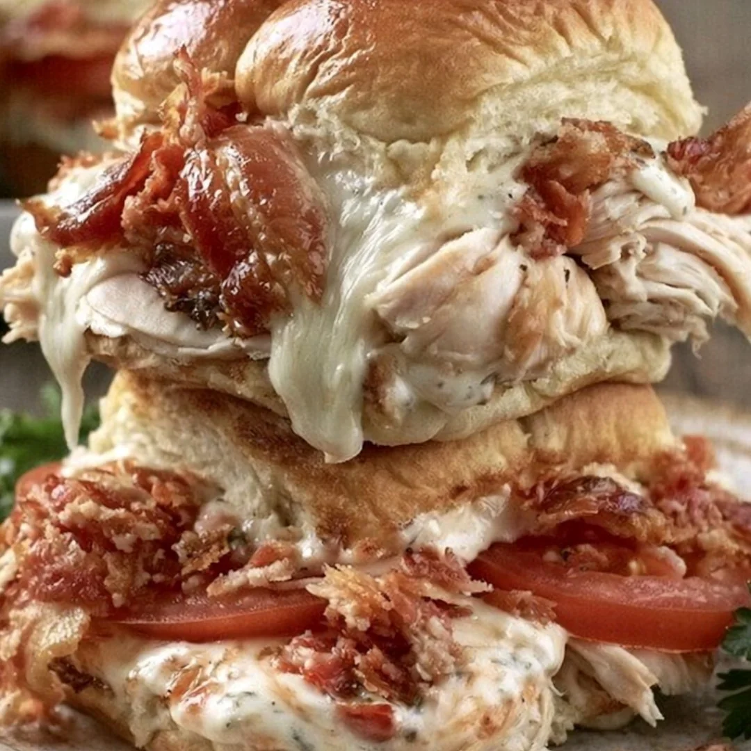Kentucky Hot Brown Sliders topped with creamy sauce and bacon, served on a platter.