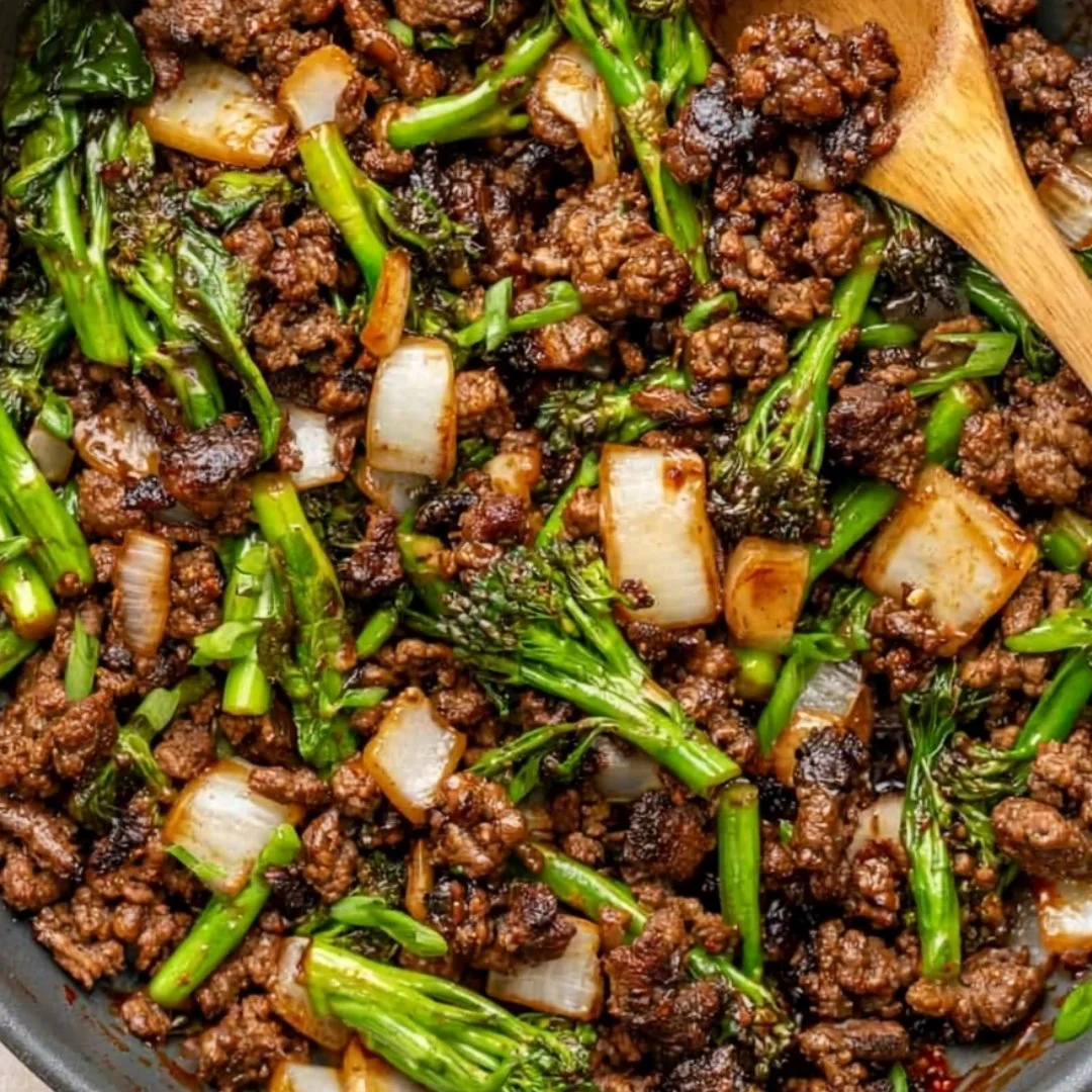 Stir fried baby broccoli with caramelized ground beef served on a plate.